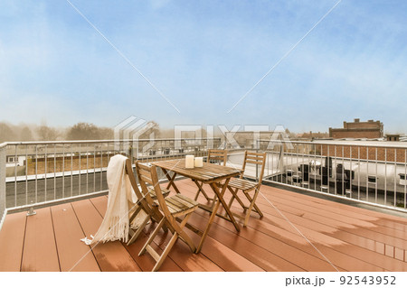 Narrow brick balcony with metal railings, wooden chair and door Narrow brick balcony with metal railings, wooden chair and door 92543952