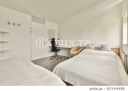 A spacious bright attic bedroom with a minimalistic workplace table and a large panoramic window 92544486