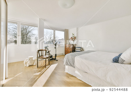 Home interior design of bedroom with bed and wooden wardrobe placed in corner near window in modern apartment Home interior design of bedroom with bed and wooden wardrobe placed in corner near window in modern apartment 92544488