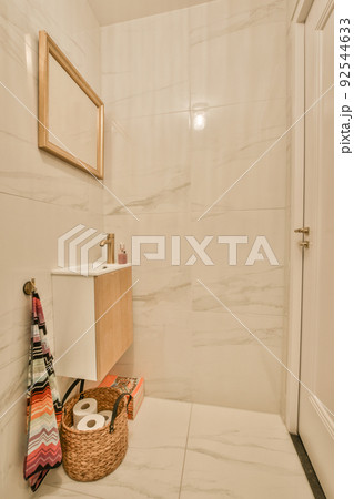 Interior of narrow restroom with sink and wall hung toilet with white walls and checkered floor 92544633