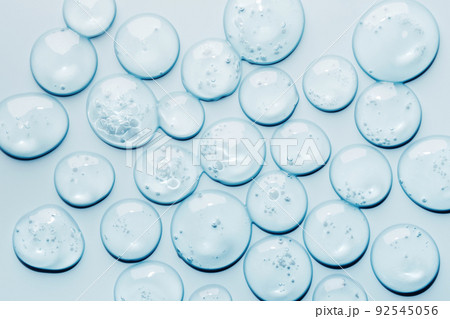 Liquid gel abstract cosmetic swatch drops on blue background. Smear of transparent moisturizing product Liquid gel abstract cosmetic swatch drops on blue background. Smear of transparent moisturizing product 92545056