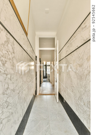 Light narrow hallway with many doors in white walls and glowing lamp over lumber floor 92545662