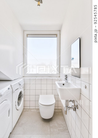 Wall hung toilet and small sink in corner in lavatory room with beige tile Wall hung toilet and small sink in corner in lavatory room with beige tile 92545785