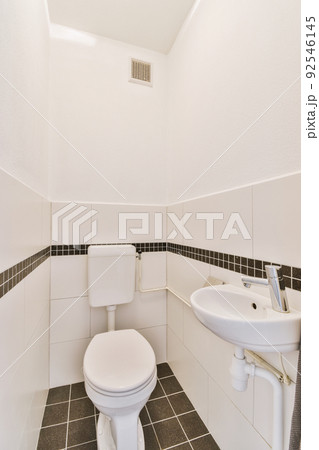 Bathroom with white tiled walls and open shower near sink with toilet in light Bathroom with white tiled walls and open shower near sink with toilet in light 92546145
