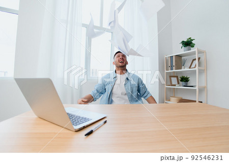 Crazy screaming irritated handsome stylish young businessman throws the paper over the table out of anger. Copy space for ad. Remote Job, Technology And Career Profession Concept 92546231