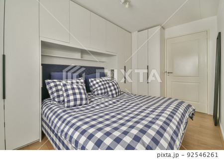 Comfortable bed with colorful pillows and warm blanket located near window in stylish bedroom with green walls Comfortable bed with colorful pillows and warm blanket located near window in stylish bedroom with green walls 92546261