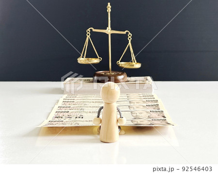 お札の上に乗った天秤の前の人形 92546403