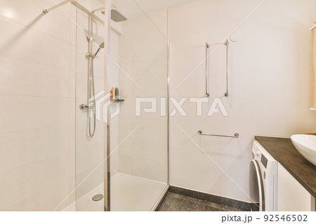 Contemporary bathroom with bathtub and glass shower cabin with light tile and white ceiling Contemporary bathroom with bathtub and glass shower cabin with light tile and white ceiling 92546502