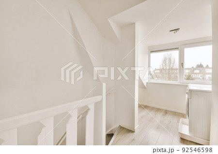 Interior of empty white room with large balcony windows with curtains and wooden parquet floor 92546598
