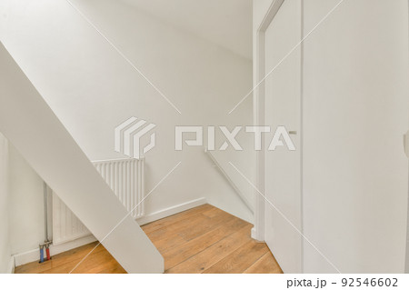 From above of narrow spiral stairway with white stairs and railing on wall inside of modern apartment 92546602