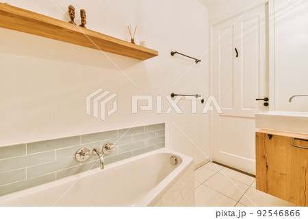 Sinks with mirrors and clean bathtub in modern bathroom with white tiled walls 92546866
