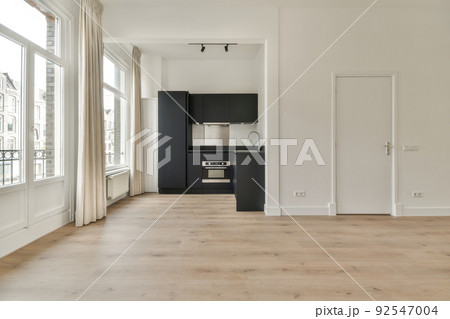 An empty bright room with a window and a minimalistic stylish kitchen corner An empty bright room with a window and a minimalistic stylish kitchen corner 92547004