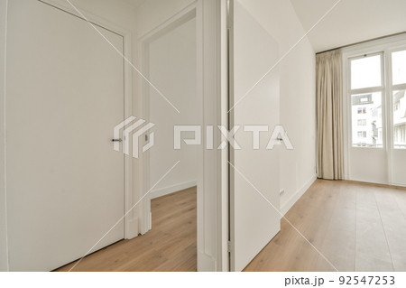 Interior of empty modern apartment with geometric design with entrance door and white walls and parquet floor illuminated with lamp 92547253