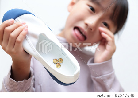 上履きに画鋲が入っていてショックを受ける小学生の女の子 92547649