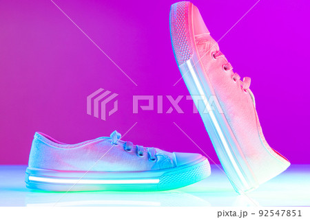Female white sports shoes, sneakers isolated over purple neon background. Urban city fashion, fitness, sport, training concept. 92547851