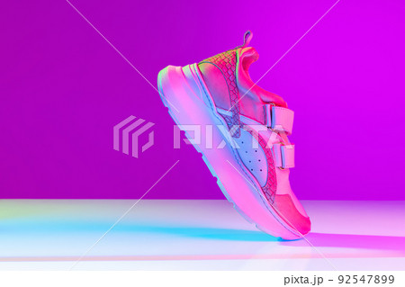 One sports shoe isolated over neoned background. Urban city fashion, fitness, sport, training concept. 92547899