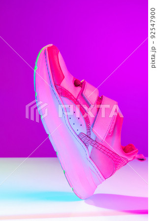 Unisex sports shoes, sneakers isolated over purple neon background. Urban city fashion, fitness, sport, training concept. 92547900