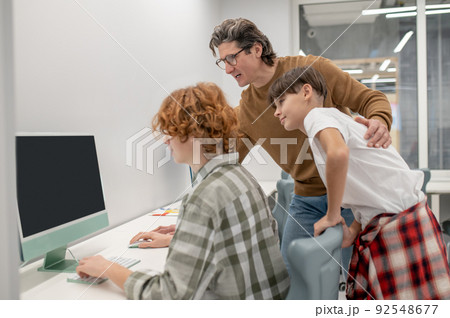 Schoolboys and their teacher at the computers in a classroom Schoolboys and their teacher at the computers in a classroom 92548677
