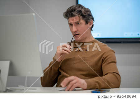 A man sitting at the computer and looking concentrated 92548694