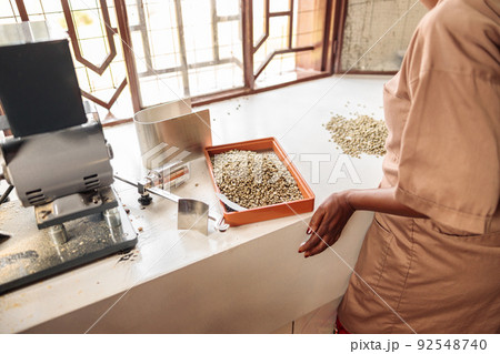 Female worker standing near the table and sorting coffee beans Female worker standing near the table and sorting coffee beans 92548740