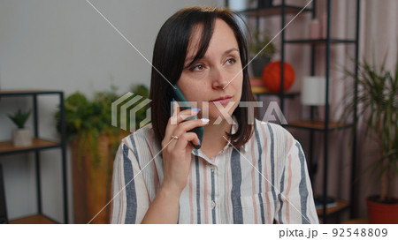 Young woman freelancer answering to client on mobile phone call, using smartphone, home office 92548809