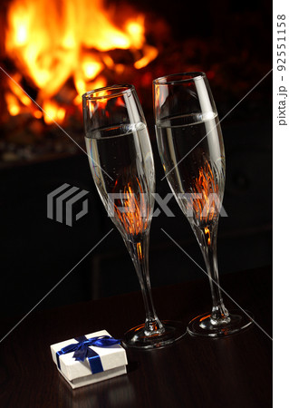 glasses with champagne and a gift, fire as the background 92551158
