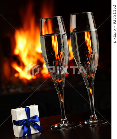 glasses with champagne and a gift, fire as the background 92551162