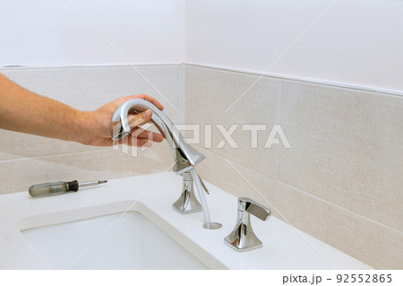 A plumber assembles a water faucet for the bathroom and installs 92552865