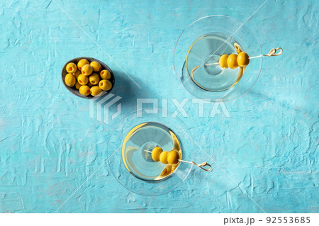 Martini, two glasses with spicy olives, on a blue background Martini, two glasses with spicy olives, on a blue background 92553685