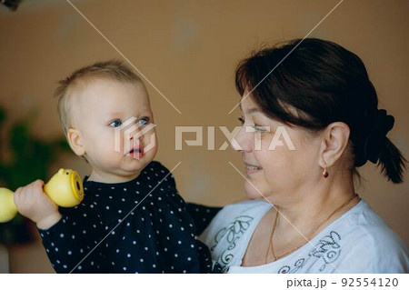 little caucasian baby girl and grandmother. woman hugging granddaugher with love little caucasian baby girl and grandmother. woman hugging granddaugher with love 92554120