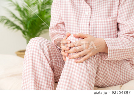 パジャマ姿で足を押さえるミドル女性 92554897