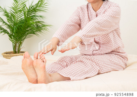 パジャマを着て布団でストレッチをするミドル女性 92554898