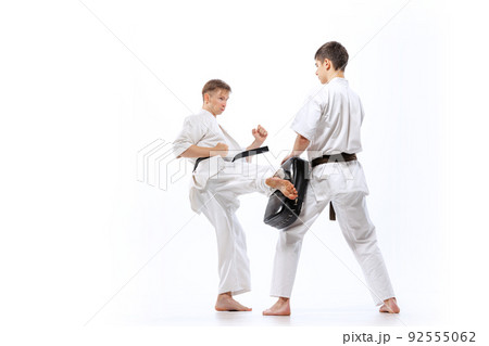 Two athletes, karate-do fighters in doboks practicing karate isolated on white background. Concept of sport, education, skills, martial arts, healthy lifestyle 92555062