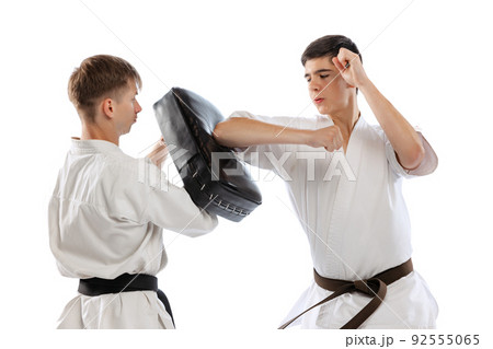 Two athletes, karate-do fighters in doboks practicing karate isolated on white background. Concept of sport, education, skills, martial arts, healthy lifestyle Two athletes, karate-do fighters in doboks practicing karate isolated on white background. Concept of sport, education, skills, martial arts, healthy lifestyle 92555065