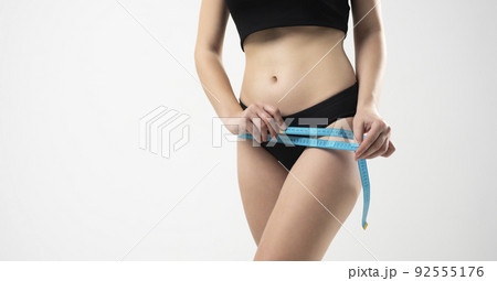 Front view of woman girl taking measurements of her body on white background with a measuring tape. Front view of woman girl taking measurements of her body on white background with a measuring tape. 92555176