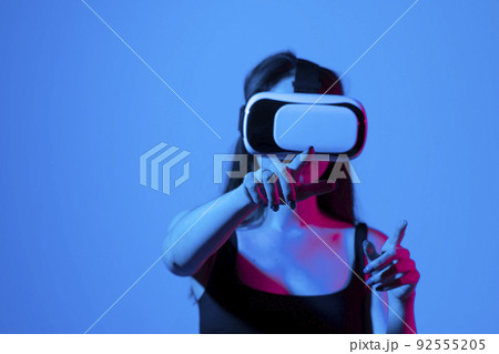 Woman using VR virtual reality glasses headset pointing at objects in metaverse. Virtual reality metaverse. 92555205