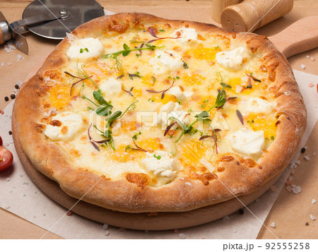pizza four cheeses on a wooden board in a restaurant 92555258