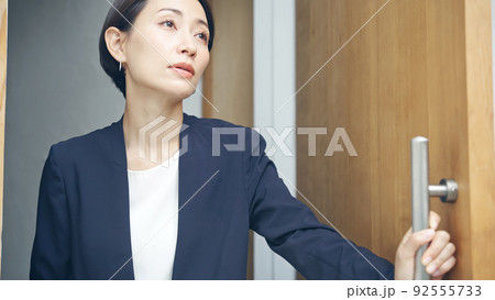 憂鬱な表情でドアを開ける女性 92555733