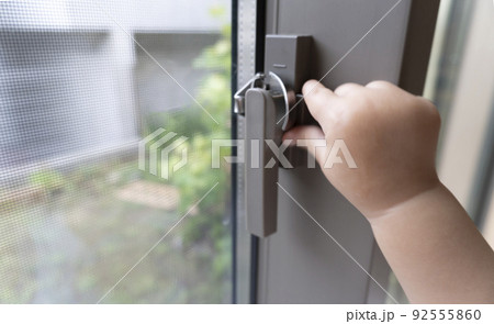 窓ガラスのクレセントを外そうとする赤ちゃんの手 92555860