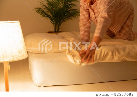 パジャマを着て布団を整えるミドル女性 92557095