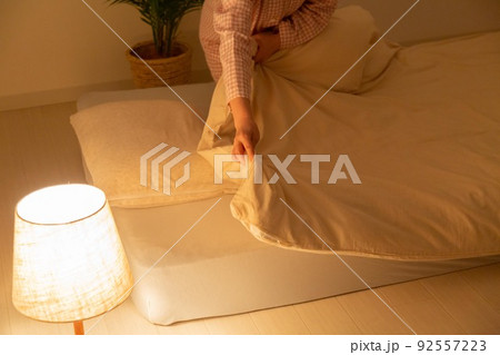 パジャマを着て布団を整えるミドル女性 92557223