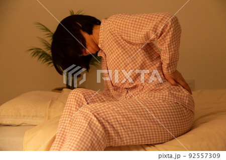 パジャマ姿で腰痛に苦しむミドル女性 パジャマ姿で腰痛に苦しむミドル女性 92557309
