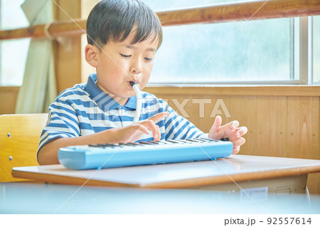 教室で鍵盤ハーモニカを演奏する小学生の男の子 教室で鍵盤ハーモニカを演奏する小学生の男の子 92557614