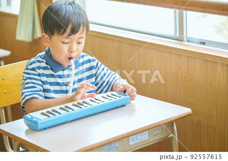 教室で鍵盤ハーモニカを演奏する小学生の男の子 92557615