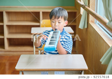 教室で鍵盤ハーモニカを演奏する小学生の男の子 教室で鍵盤ハーモニカを演奏する小学生の男の子 92557618