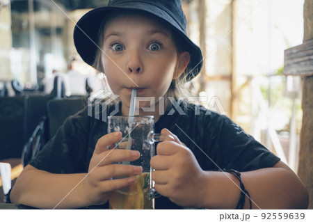 Little girl with a mug of lemonade in a cafe. High quality photo Little girl with a mug of lemonade in a cafe. High quality photo 92559639