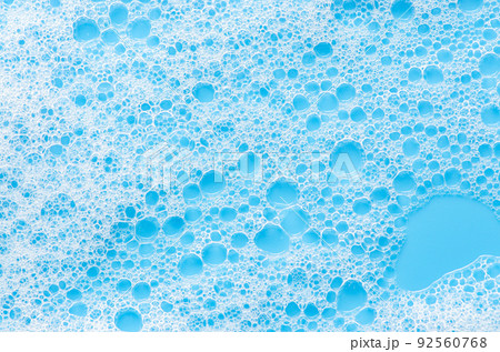 Texture of white foam on a blue background. Cleansing mousse for the face or bath foam or washing powder. Closeup Texture of white foam on a blue background. Cleansing mousse for the face or bath foam or washing powder. Closeup 92560768