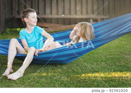 children brother and sister resting in the garden on a hammock 92561020