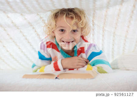 Child reading book in bed. Kids read books. 92561127