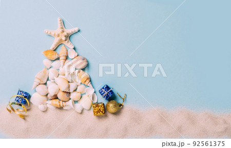 Creative Christmas tree from sea shells, small gifts blue background. Concept tropical new year Creative Christmas tree from sea shells, small gifts blue background. Concept tropical new year 92561375